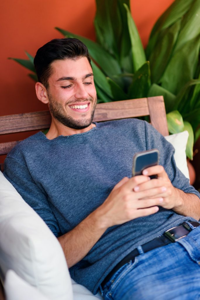 Cheerful man browsing smartphone in room